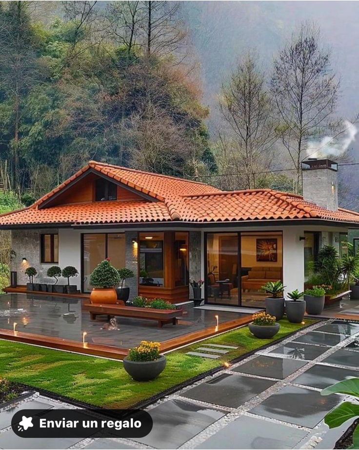 the house is surrounded by lush green trees and greenery, with an orange tiled roof