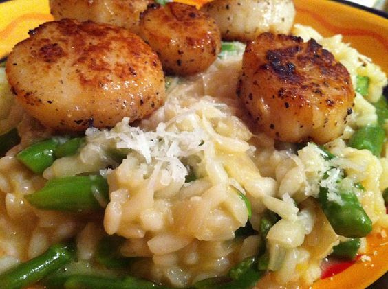 some scallops are on top of pasta and asparagus in a yellow bowl