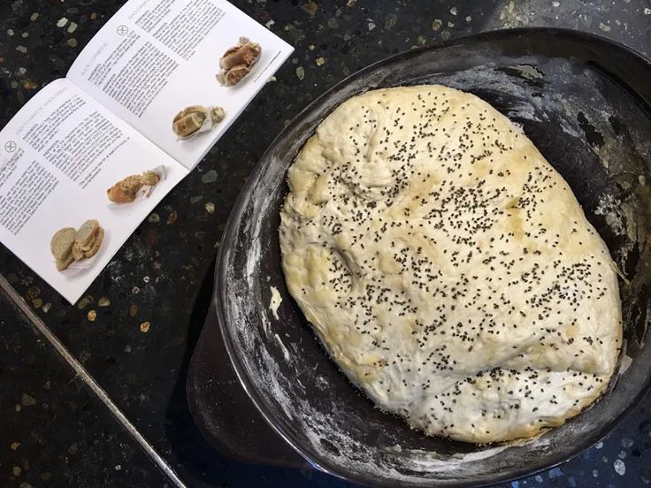 an uncooked bread in a skillet next to an open book