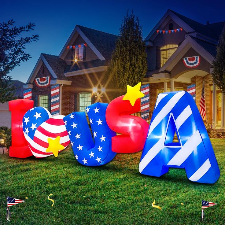 large letters with stars and stripes are in front of a lit up american flag house