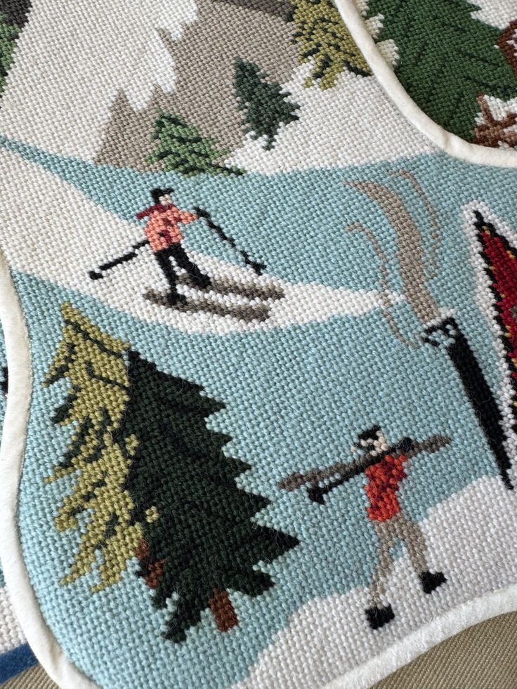 a close up of a cross stitch pattern on a blanket with people skiing and snowboarding