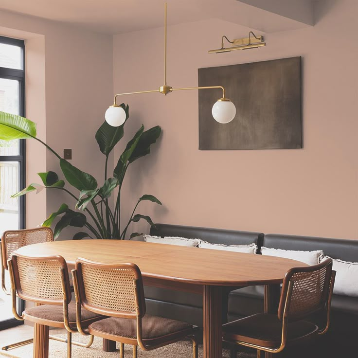 a dining table with four chairs and a plant in the corner next to an open window