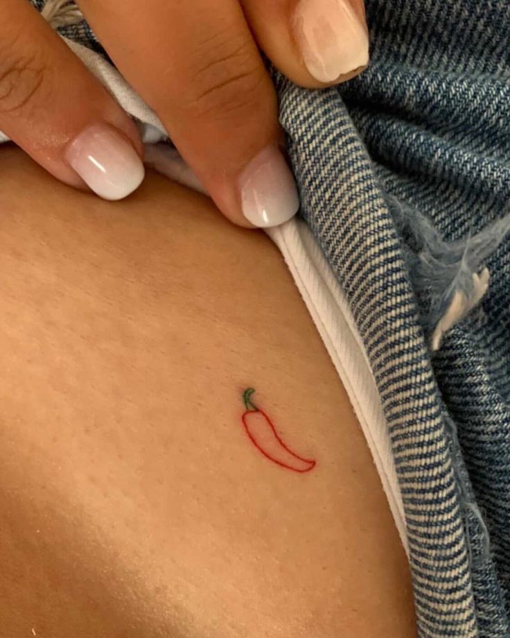 a woman's leg with a tiny red chili on the lower part of her thigh