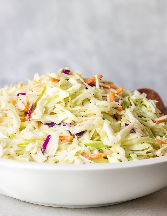 a white bowl filled with coleslaw slaw and carrots on top of a table