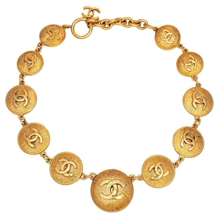 Vintage 80s Chanel medallion necklace crafted in yellow gold-tone (circa early 1980s). The necklace features 'CC' logo medallions that graduate in size from 22mm (0.86 inches) to 32mm (1.25 inches). Measuring 17 inches in length the necklace is slightly adjustable to 15 1/2 inches. The medallions are in very good condition (no chips or flaking). The necklace comes with the original Chanel box. The necklace is in very good condition showing minimal wear. Particulars: Weight: 90.8 grams Size & Measurements: The necklace measures 17 inches in length and is slightly adjustable to 15 1/2 inches. The medallions graduate in size from 22mm (0.86 inches) to 32mm (1.25 inches). Metal & Hallmark: Yellow gold tone. The necklace is hallmarked "Chanel", "Made in France", and "CC" and dates to the early 80s Chanel, Men's Necklace Gold, Chanel Medallion, 80s Jewelry, Vintage Gold Necklace, Chanel Box, Daisy Jones, Vintage Medallion, Necklace Craft