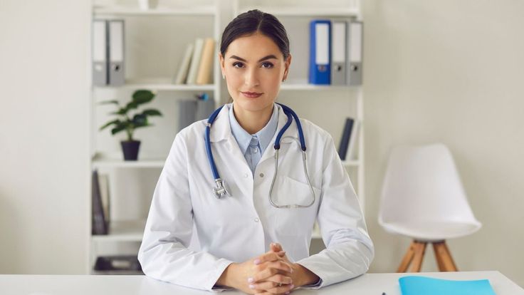 a female doctor sitting at a desk in front of a laptop