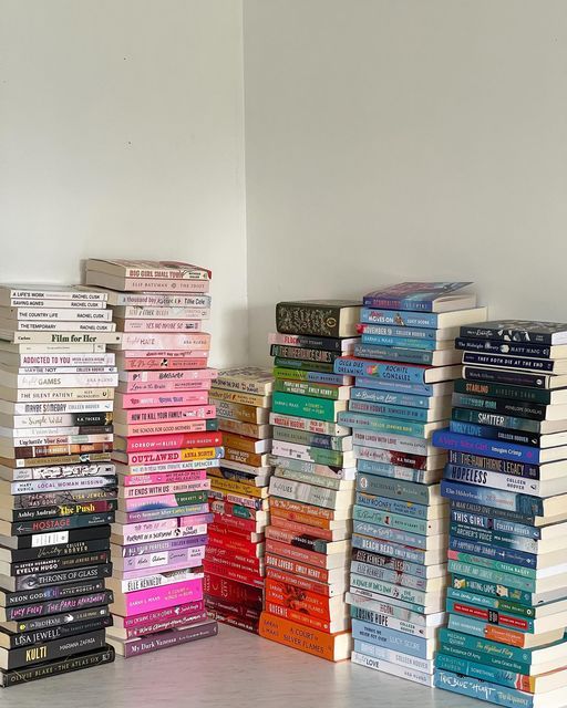 a stack of books sitting next to each other on top of a white floor in front of a wall