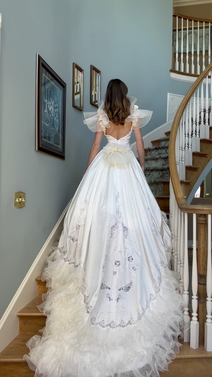 a woman in a wedding dress walking down the stairs with her back to the camera