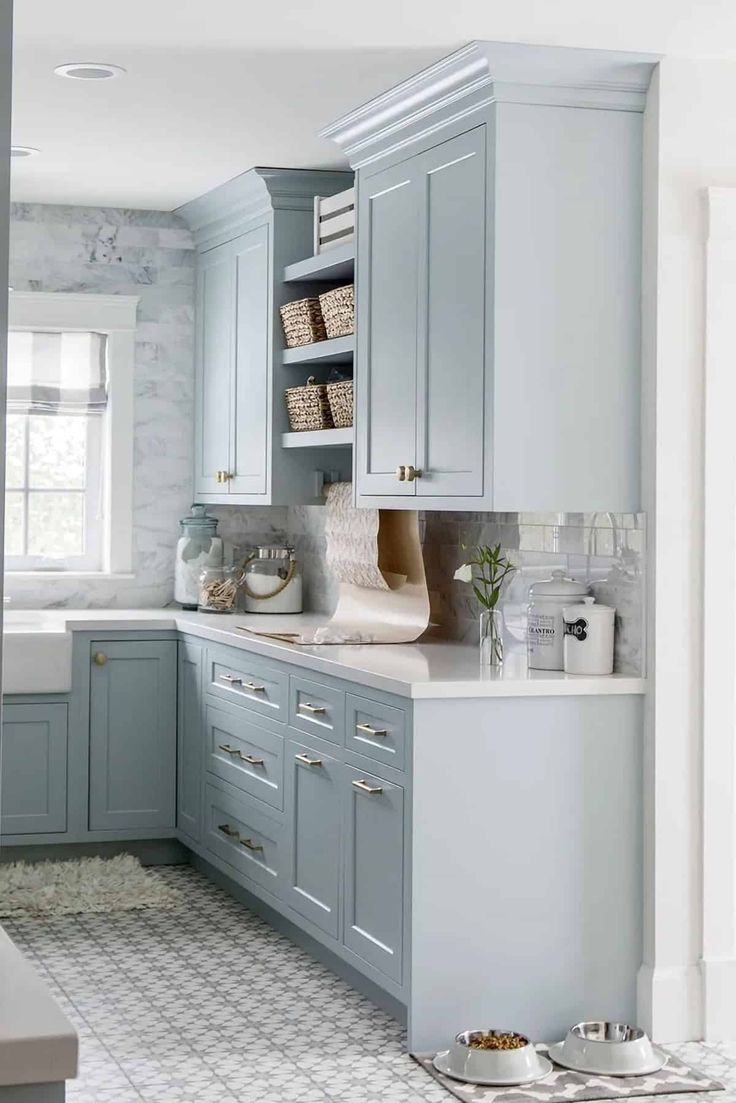 a kitchen with blue cabinets and white counter tops, along with dishes on trays