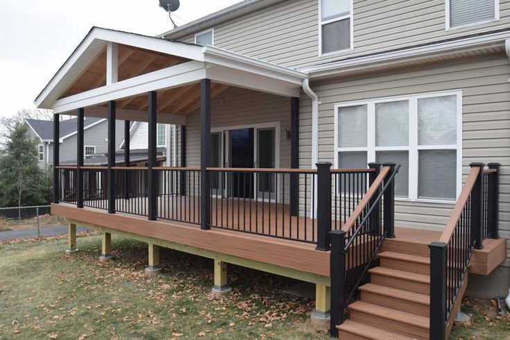 a wooden deck with black railings next to a house