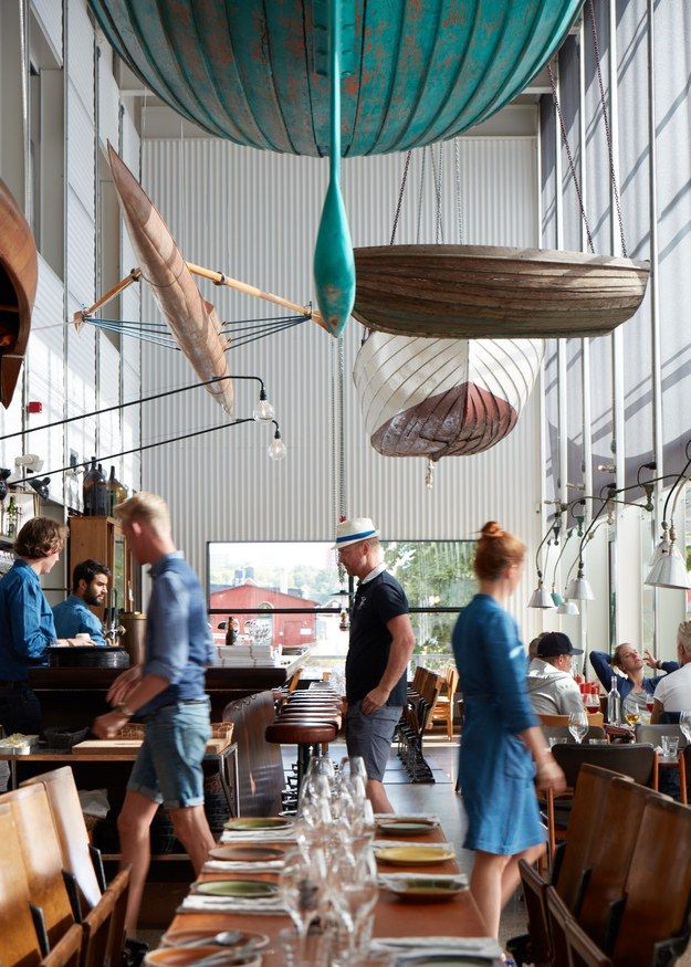 people are eating at tables in a restaurant with hanging lights above them and plates on the table