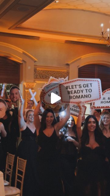 a group of people holding up signs in front of a room with chandeliers