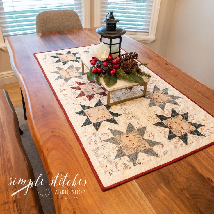 a table with a christmas centerpiece on top of it and a lantern in the background