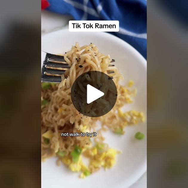 a white plate topped with noodles and veggies next to a fork on top of it