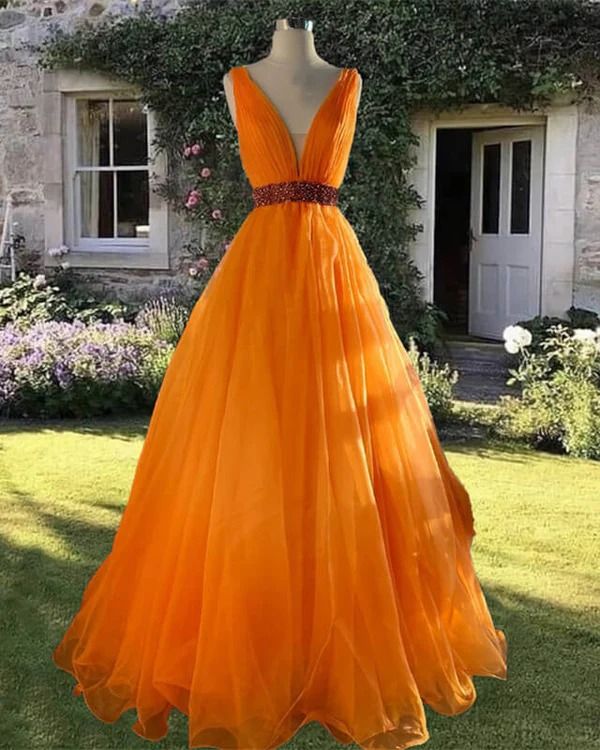 an orange dress is on display in front of a house with flowers and greenery