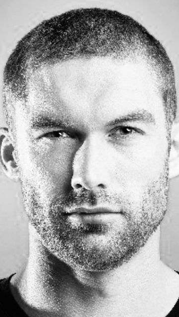 a black and white photo of a man with short hair wearing a t - shirt