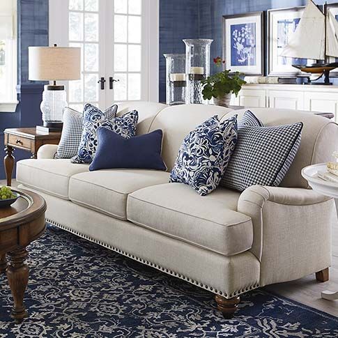 a living room filled with furniture and blue pillows on top of it's couches