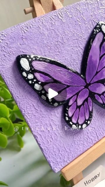 a purple butterfly sitting on top of a wooden easel