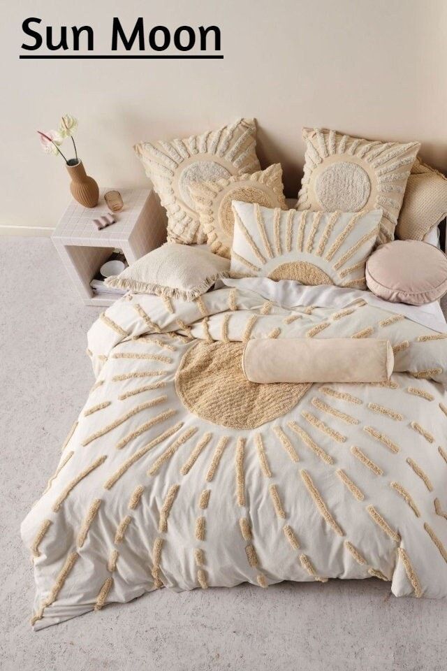 a bed with white and gold comforters in a bedroom next to a nightstand on the floor