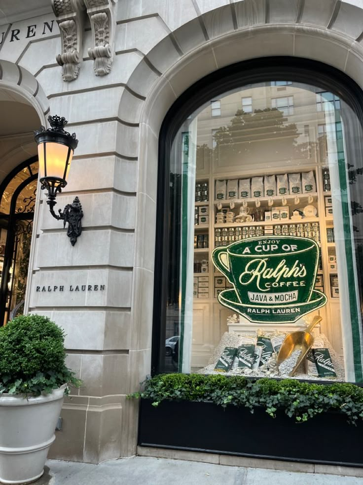 a store front window with an advertisement in the window and potted plants on the sidewalk