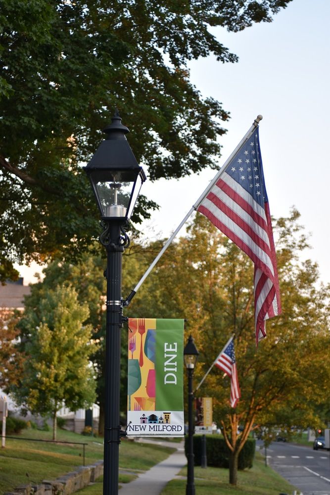 an american flag is hanging on a lamp post in front of a street sign and flags