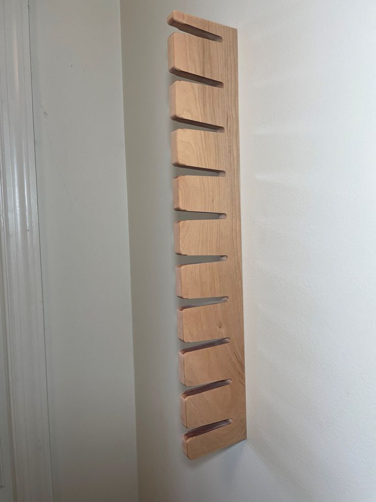 a wooden rack mounted to the side of a wall next to a white wall and door