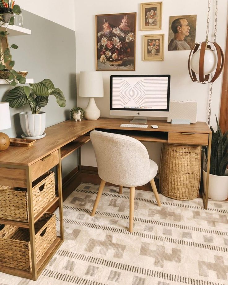 a desk with a computer on top of it next to a chair and potted plant