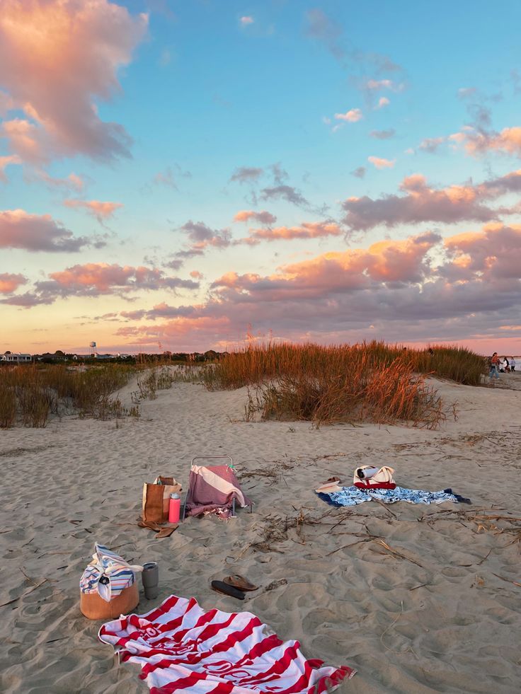 an american flag laying on top of a sandy beach next to the ocean at sunset