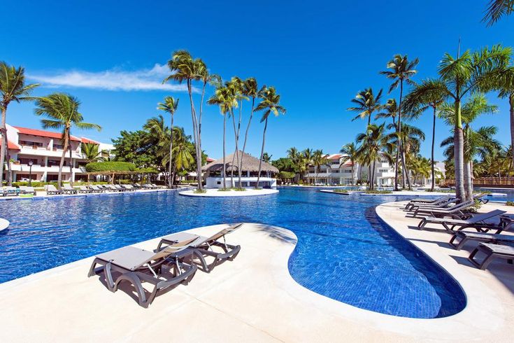 an empty swimming pool with lounge chairs and palm trees in the background at a resort