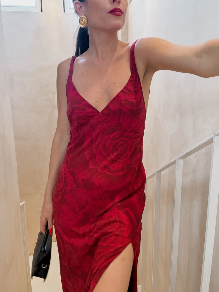 a woman in a red dress is holding her hand out to the side while standing on stairs