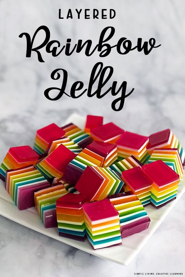 layered rainbow jello on a plate with the words layered in black and white