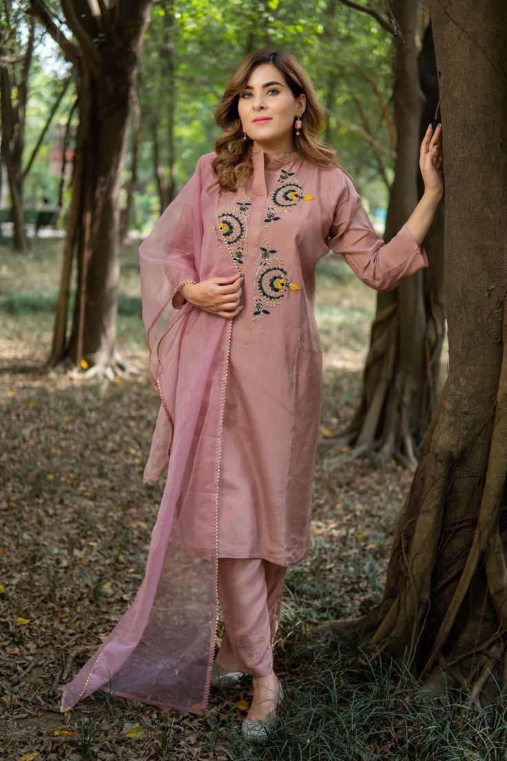 Highlights Handmade Color: Onion Pink Product Type: Kurta, Pant & Dupatta Fabric: Cotton Silk Embroidered: Zardozi Work  Style: Straight Neckline: collar neck design Occasion: Festive Wear Sleeves: 3/4 Sleeves Length: Calf Length Gender: Women Pattern: Embroidered Package contains: Kurta & Pant with Orgenja Dupatta Care Instructions: Dry clean Description Our Zardozi Hand Work Kurti Set in Onion Pink color is a true embodiment of luxury and craftsmanship. Handcrafted with meticulous attention to detail, this set showcases the exquisite art of zardozi work, resham thread, and golden thread embroidery. The onion pink color adds a touch of femininity and sophistication. The straight style of the kurti exudes elegance, while the collar neck design adds a regal charm. The 3/4 sleeves strike a b Embroidered Chanderi Pant Set, Zari Work Pant Set For Summer, Chanderi Pant Set For Diwali, Spring Cotton Silk Sets With Zari Work, Pink Pant Set With Straight Kurta, Unstitched Cotton Silk Palazzo Set, Pink Pant Set With Dabka Work, Spring Salwar Kameez With Dori Work, Elegant Churidar With Dori Work