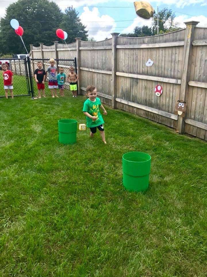 a young boy playing with plastic buckets in the yard