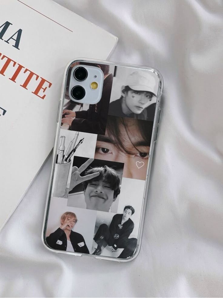 an iphone case with photos on it sitting next to a book and white satin material