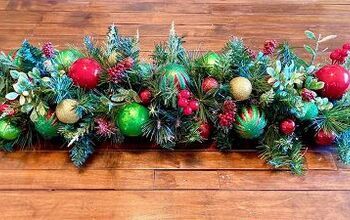 a wooden table topped with lots of christmas decorations on top of green leaves and red balls