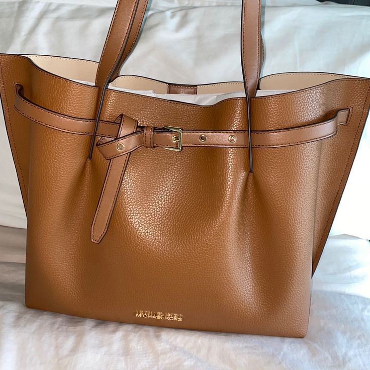 Michael Kors Emilia Large Tote Shoulder Bag. Nwt. Made Of 100% Pebbled Leather. Camel Color. Comes With Dust Bag. Gold-Tone Hardware 16.75”W X 11.5”H X 8.5”D Handle Drop: 11.25” Compatible With 13” Laptop Interior Details: Back Zip Pocket, Center Zip Compartment, 6 Front Slip Pockets Lining: 100% Polyester Snap Fastening Light Brown Leather Bags With Gold-tone Hardware, Caramel Leather Bag With Leather Handles, Caramel Tote Bag For Shopping, Luxury Caramel Everyday Shoulder Bag, Cognac Shoulder Bag With Gold-tone Hardware, Cognac Shoulder Bag With Gold-tone Hardware For Errands, Cognac Bag With Gold-tone Hardware For Errands, Caramel Leather Bag With Gold-tone Hardware, Caramel Leather-lined Travel Bag