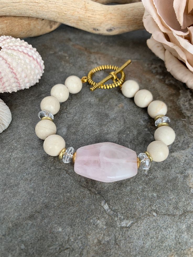 Pretty in pink gemstone beaded bracelet ... handcrafted with a soft pink Rose Quartz focal bead with creamy River Jasper beads paired with crystal clear Quartz beads accented with African Brass beads . This lovely Spring inspired piece measures 7 inches in length with a rope textured Brass toggle clasp . Beaded Rose Quartz Crystal Bracelet, Healing Pink Bracelets With Spacer Beads, Rose Quartz Beaded Bracelets With Faceted Beads, Rose Quartz Faceted Beaded Bracelets, Spiritual Beaded Rose Quartz Crystal Bracelet, Spiritual Rose Quartz Beaded Crystal Bracelet, African Brass Beads, Pretty Rose, Pink Rose Quartz