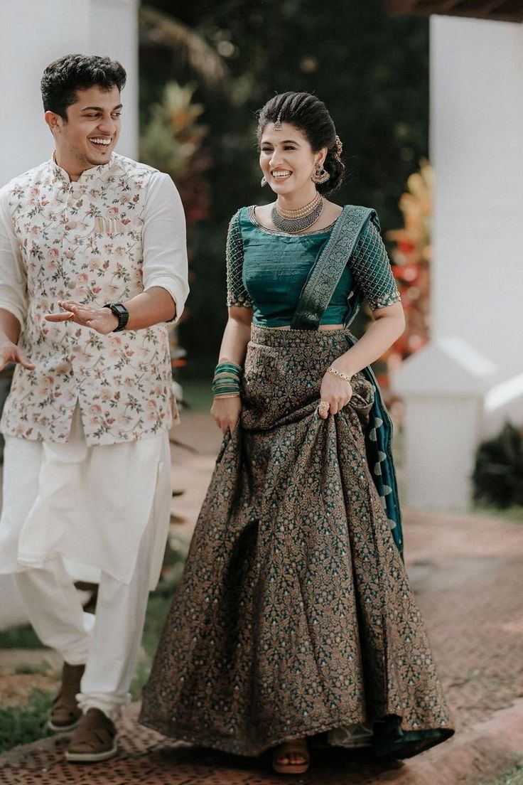 a man standing next to a woman in a green and white dress on a sidewalk