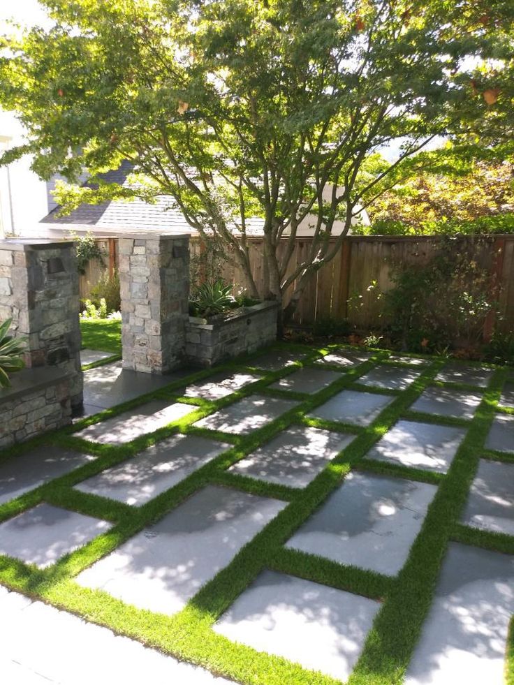 an outdoor area with grass and stone blocks in the center, surrounded by a tree