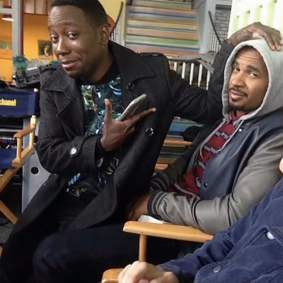 three men sitting in chairs with one holding a cell phone and the other pointing at something