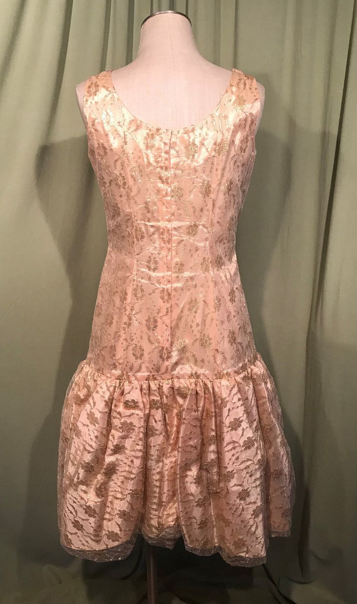 "This is a vintage formal dress from the early 60s. No labels or tags. The bust measures 36\", waist 30\", see measurements below, but it would look best on a slightly smaller bust & waist. Made of gold lace over a satin underlayer. It is a drop waist dress with bubble hemline. It is sleevless with a wide neckline. The bubble skirt is gathered & lined with pellon for stiffness & fullness. The skirt is trimmed to one side with a swoop of fabric & a gold metallic, fabric rose. Zips Fitted A-line Vintage Dress With Ruffles, Vintage Knee-length Prom Dresses, Fitted 1950s Style Dresses For Vintage Events, Elegant Fitted Vintage Dress For Vintage Fashion, 1950s Style Vintage Dress For Events, 1950s Fitted Prom Dresses, Elegant Fitted Vintage Dress, 1950s Formal Ruffled Dress, 1950s Style Ruffled Formal Dresses