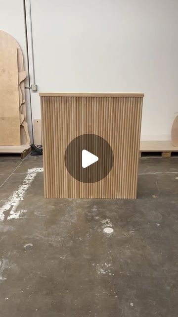 a wooden box sitting on top of a cement floor next to a wall with a video player in it