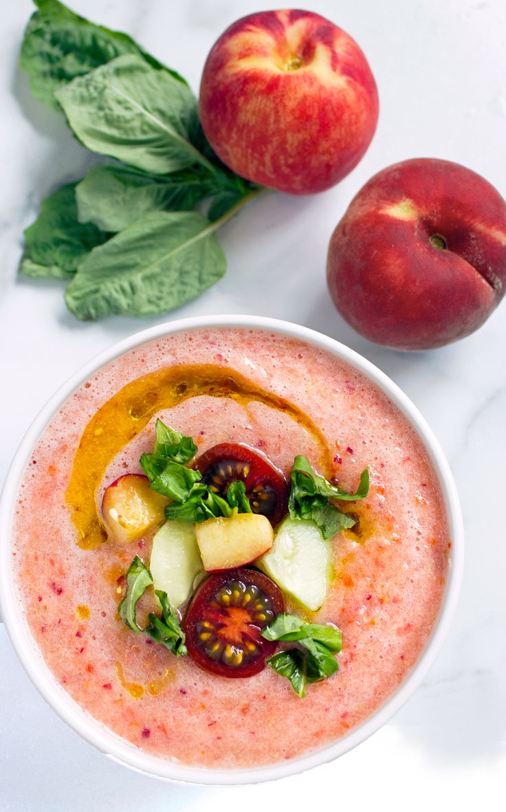 a white bowl filled with food next to two peaches