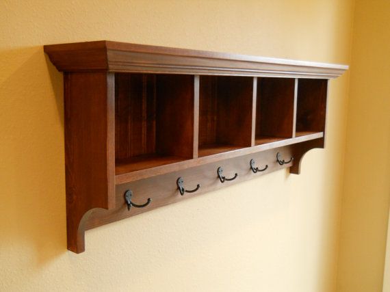 a wooden shelf with three hooks on it