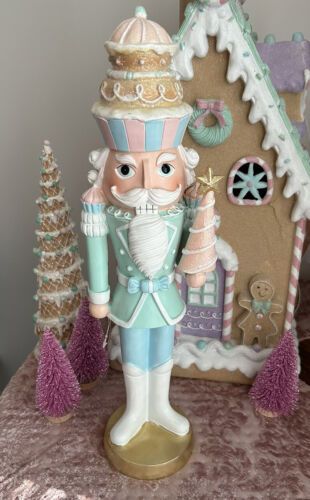 a nutcracker figurine stands in front of a gingerbread house