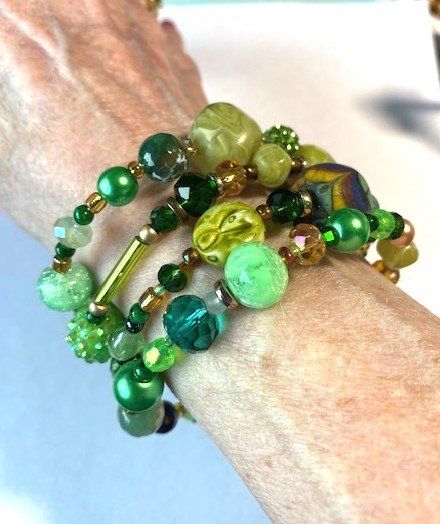 This green beaded bracelet wraps 4 times around the wrist.  It features a hand painted bead, two vintage wooden beads dating from a 1950s necklace, two olive green plastic beads from a 60's necklace, czech crystal beads in several shades of green, unique glass beads and some small vintage pearls.  It will match any green clothes you have because every hue of green possible is represented.  It is bling in a subtle way! Cheap Green Novelty Beaded Bracelets, Green Multi-strand Wooden Beads Jewelry, Bohemian Green Bracelets With Colorful Beads, Adjustable Green Beaded Bracelets With Wooden Beads, Green Multi-strand Bracelet With Colorful Beads, Green Multi-strand Bohemian Wrap Bracelet, Adjustable Colorful Beaded Jade Jewelry, Adjustable Jade Jewelry With Colorful Beads, Green Wrap Bracelet With Colorful Beads