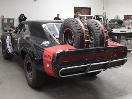 the back end of a black and red car with large tires on it's flatbed