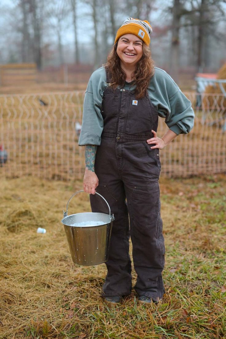 a woman in overalls holding a bucket