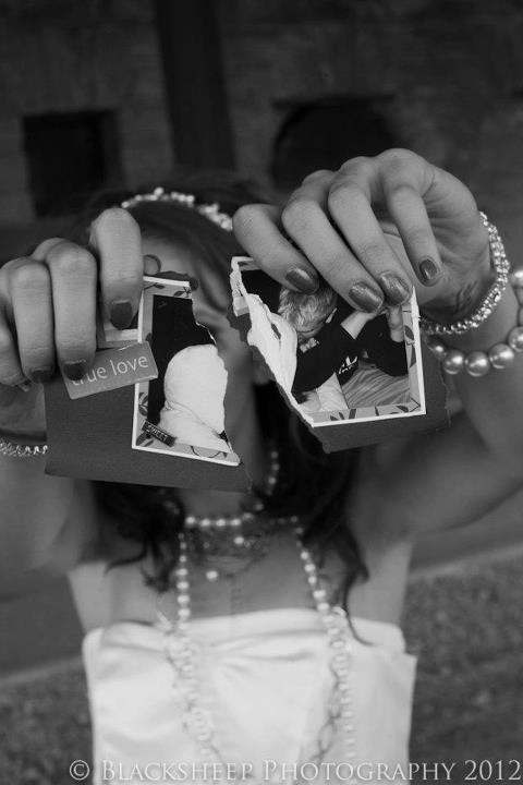 black and white photograph of a woman holding two photos in front of her face with both hands