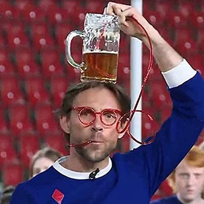 a man with glasses holding up a beer mug in front of his head while wearing a red tie